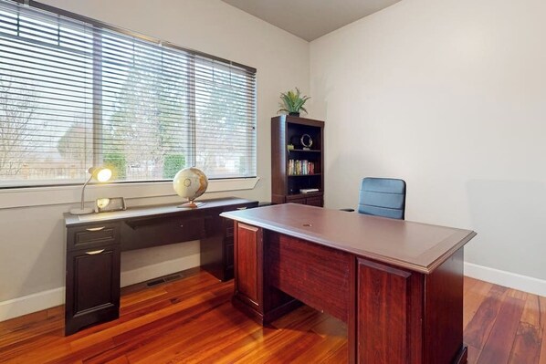 A room with a large wooden desk, a bookshelf, a globe, and a chair.