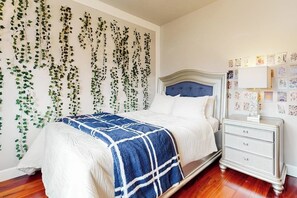 A bedroom with a bed, a nightstand, and a wall covered with ivy.