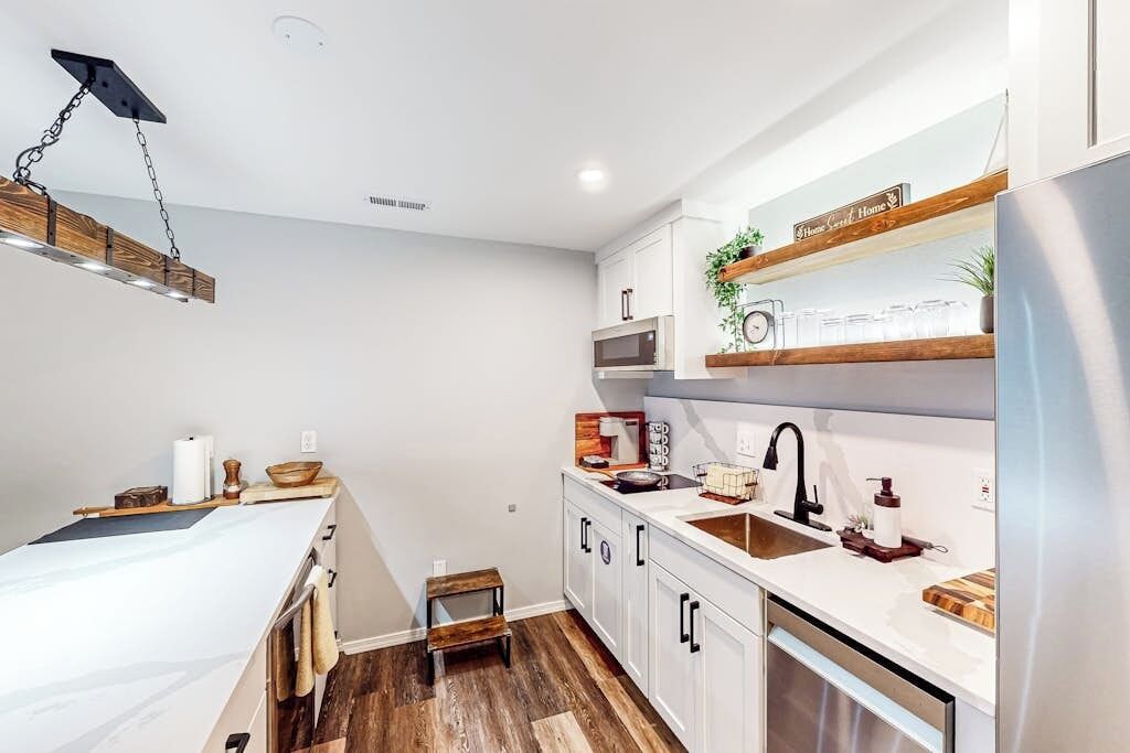 Una cocina moderna con armarios blancos, un refrigerador de acero inoxidable y una encimera de madera.