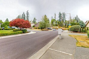 A suburban street with houses, a pedestrian crossing sign, and a sidewalk. - Modern 1BR with fireplace & inviting patio (Woodinville)
