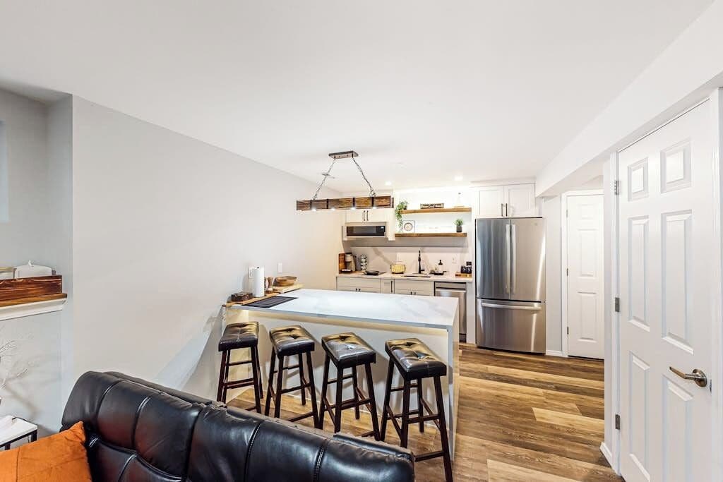 A modern kitchen with a central island, stainless steel appliances, and a bar stool seating area.