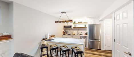 A modern kitchen with a central island, stainless steel appliances, and a bar stool seating area.