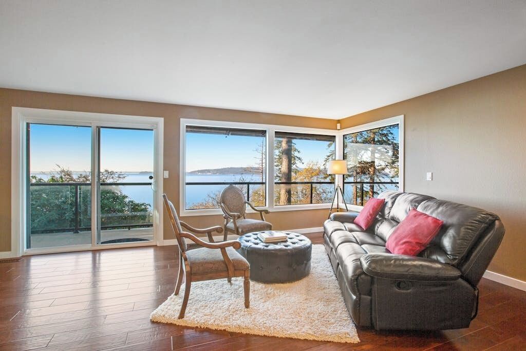 A living room with a sofa, chairs, and a view of the outdoors through large windows.