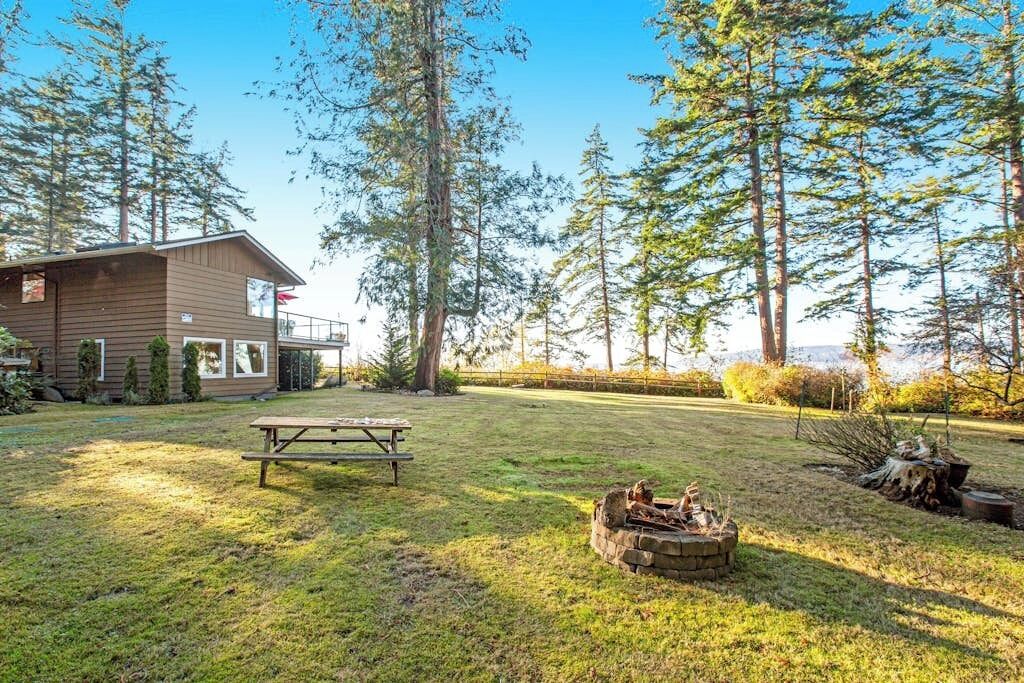 A cabin with a picnic table and a fire pit in a forested area.