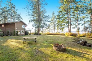 A cabin with a picnic table and a fire pit in a forested area.