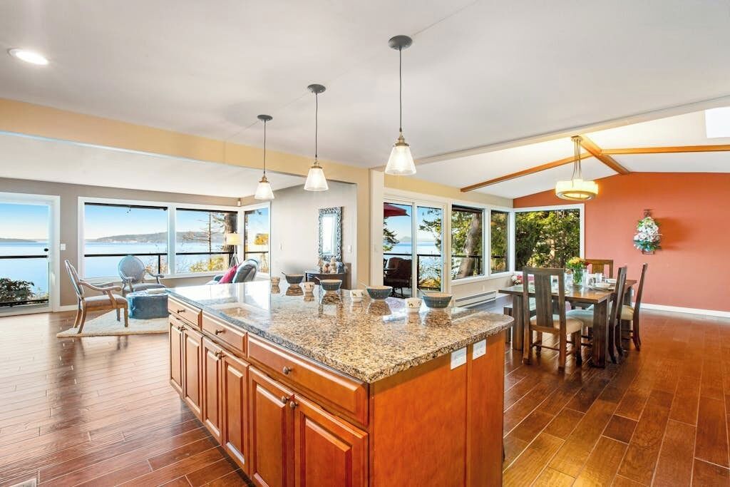 A spacious kitchen with a large island, pendant lighting, and a view of the outdoors.