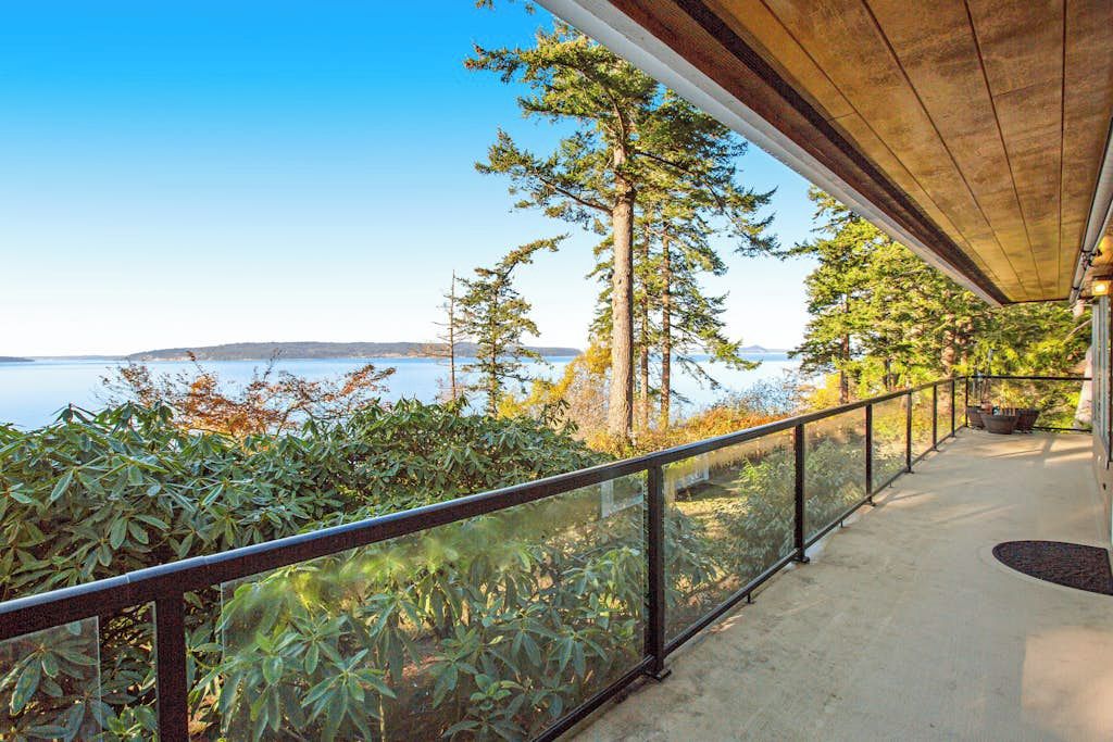 A balcony with a view of the sea and trees.