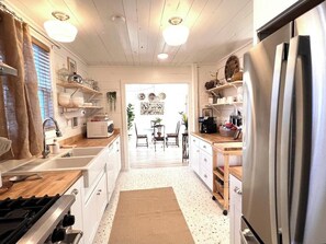 A kitchen with white cabinets, a stainless steel refrigerator, and a wooden countertop. - Stunning 1BR Oceanview -Patio -Washer Dryer- Hottub-Firepit (Moclips)