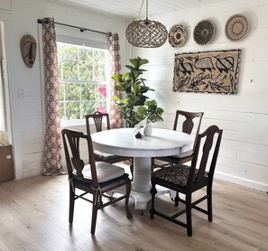 A dining area with a round table, four chairs, a potted plant, and decorative wall art. - Stunning 1BR Oceanview -Patio -Washer Dryer- Hottub-Firepit (Moclips)