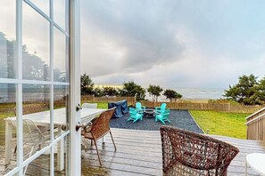 An outdoor deck with a table and chairs, a fire pit, and a view of the ocean. - Stunning 1BR Oceanview -Patio -Washer Dryer- Hottub-Firepit (Moclips)