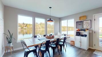 A dining area with a large table, chairs, and a view of a lake.