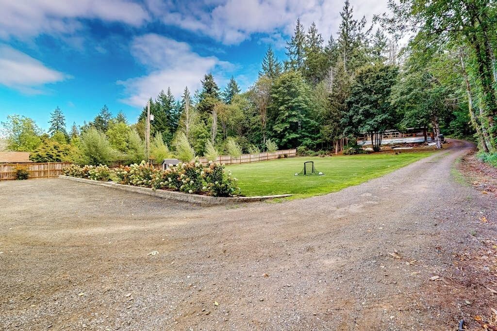 A gravel driveway leading to a wooden cabin surrounded by dense forest.