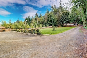 A gravel driveway leading to a wooden cabin surrounded by dense forest. - 7BR Property with water views & private beach (Shelton)