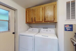A laundry room with two white washing machines and wooden cabinets above. - 7BR Property with water views & private beach (Shelton)