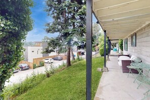 Ein überdachter Patio-Bereich mit Gartenmöbeln, Blick auf eine Wohnstraße und einen Rasen.