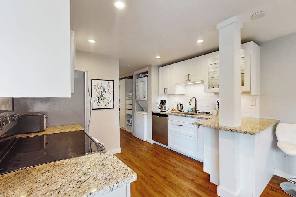 A modern kitchen with white cabinetry, a built-in oven, and a granite countertop.