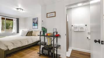 Un dormitorio con una cama, una estantería con objetos diversos, una ventana y una puerta.