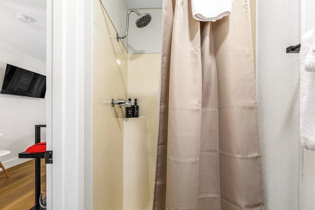 A bathroom with a shower, a towel rack, and a mounted television.