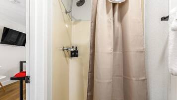 A bathroom with a shower, a towel rack, and a mounted television.