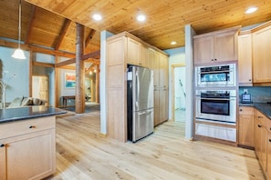 Eine geräumige Küche mit Holzausstattung, einem Edelstahlkühlschrank und einem Doppelbackofen.