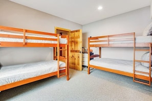 Ein Zimmer mit Etagenbetten, einem Holzschrank und einem Schreibtisch mit Stuhl.