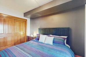 Ein Schlafzimmer mit einem großen Bett, einem Holzschrank und einem Nachttisch mit Lampe.