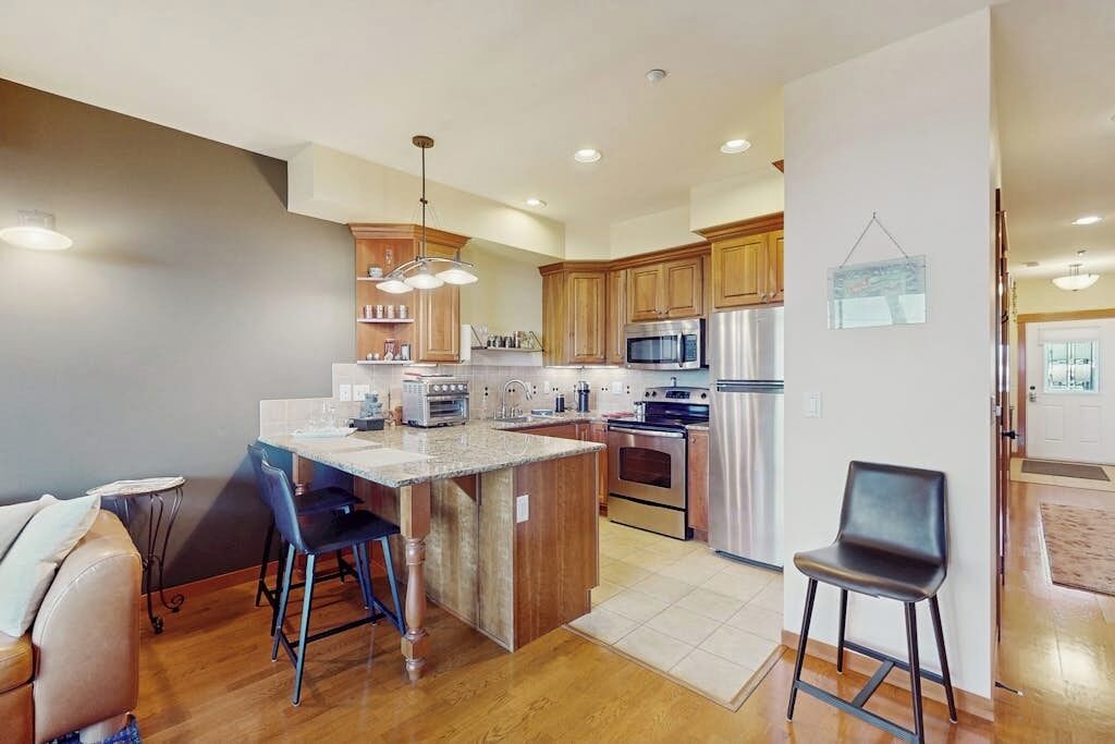 A modern kitchen with wooden cabinets, stainless steel appliances, and a central island with bar stools.
