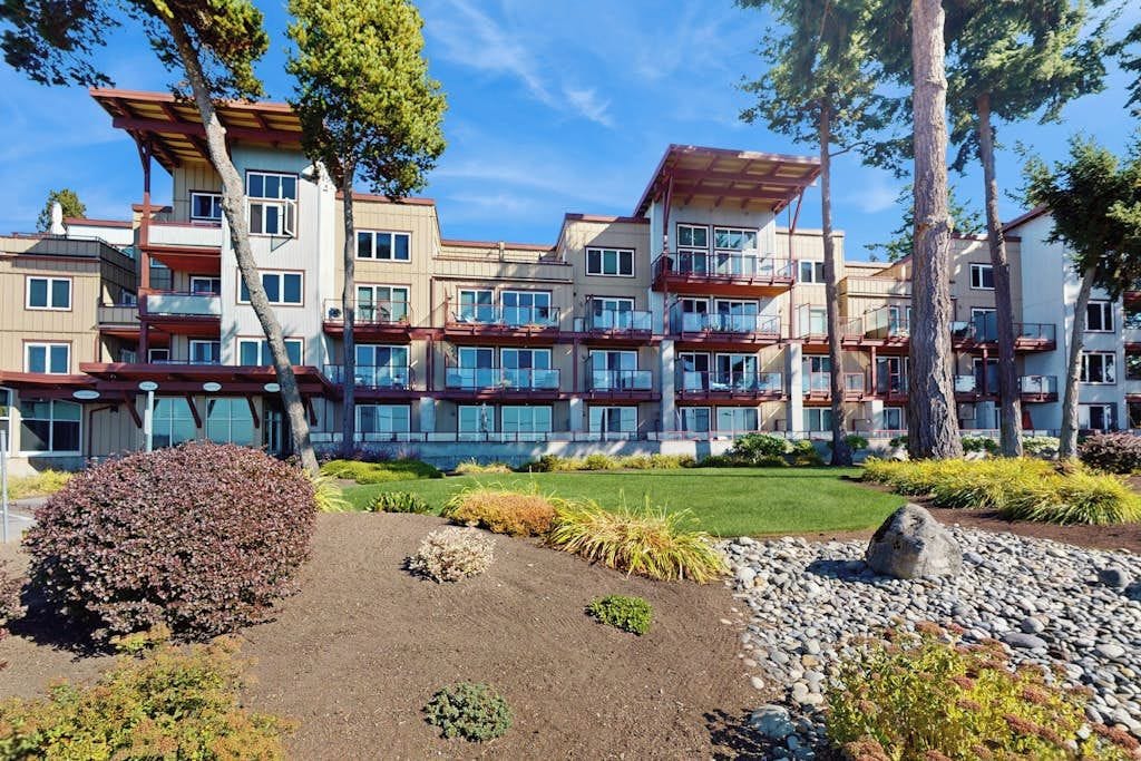 A multi-story hotel with a modern architectural design, featuring balconies and a landscaped garden area.