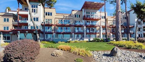 A multi-story hotel with a modern architectural design, featuring balconies and a landscaped garden area.