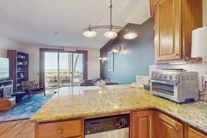 Eine moderne Küche mit Granit Arbeitsplatten, einem integrierten Geschirrspüler und einem Edelstahlbackofen.