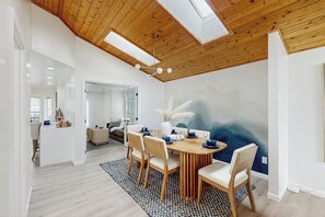 Ein Essbereich mit einem runden Tisch, Stühlen und einer Decke aus Holzbalken und Oberlichtern.