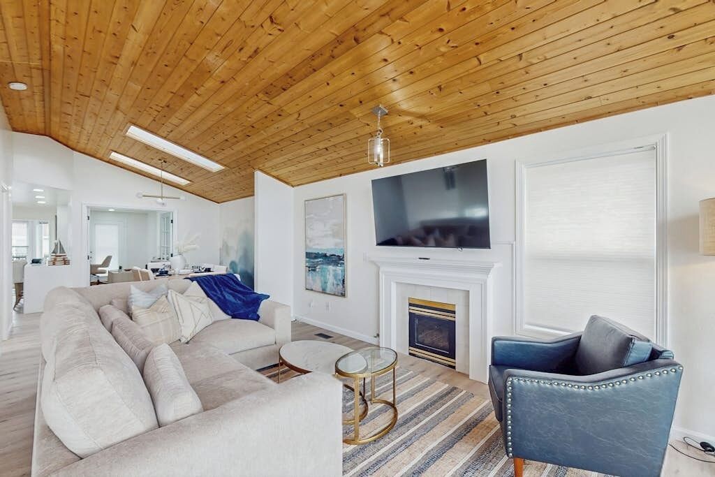 Un salon moderne avec un plafond en bois, une cheminée, un grand téléviseur et un canapé.