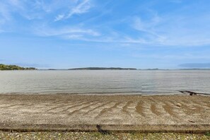 Ein Strand mit Kieselsteinen, einer Holzkonstruktion und weiter Küstenlinie.