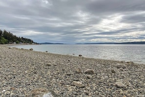 Une plage de galets, avec une eau calme et un ciel nuageux.