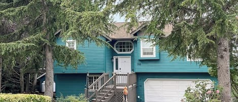 A two-story house with a front porch, a garage, and a staircase leading to the entrance.