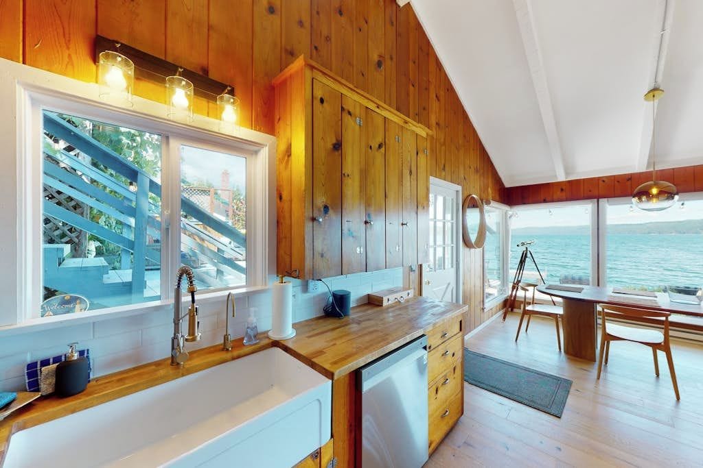 Una cocina con armarios de madera, un ventanal y vistas al mar.