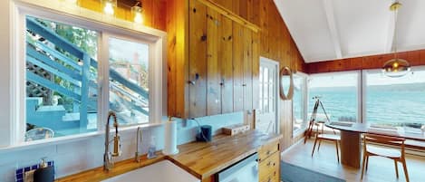 Una cocina con armarios de madera, un ventanal y vistas al mar.