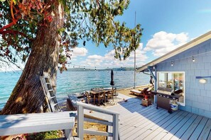 Una terraza con una parrilla y zona de estar con vista a un cuerpo de agua.