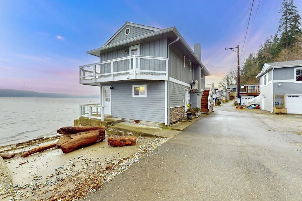 A coastal house with a balcony, a driveway, and a beachside view.
