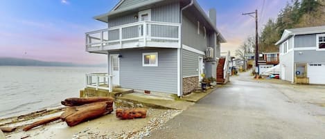 A coastal house with a balcony, a driveway, and a beachside view.