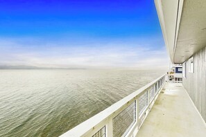 A balcony with a view of the sea, a railing, and a building facade.