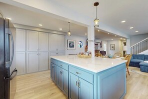 A modern kitchen with a large island, white cabinets, and pendant lighting.