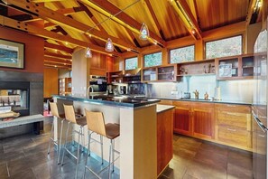 A modern kitchen with a central island, bar stools, and wooden cabinetry.