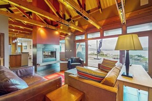 A modern interior with a fireplace, leather sofas, and a view through large windows.