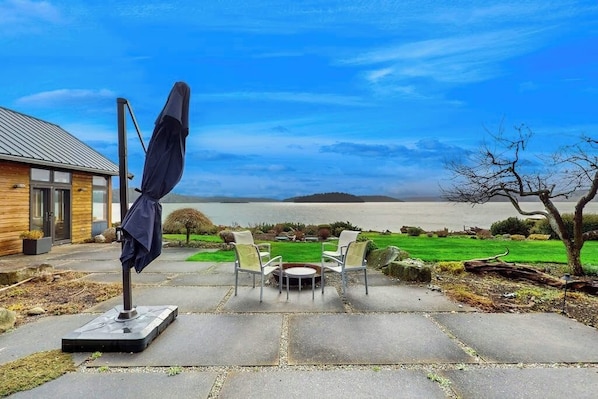 A patio with stone flooring, a round table, and two chairs.