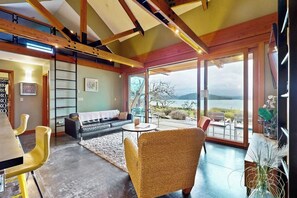 A modern interior with a dining area, sofa, and a view of the outdoors.