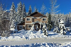 A two-story house with a brown facade, surrounded by snow-covered trees. - ski-in and out 3BR with mountain views & fireplace (Snoqualmie Pass)