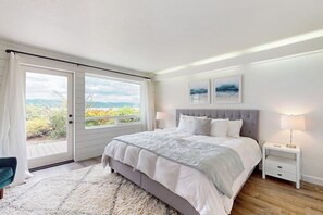 A bedroom with a large bed, a nightstand, a window with curtains, and artwork on the wall. - 2BR Waterfront Home with Private Beach Access (Belfair)