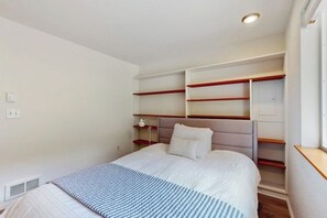 A hotel room with a bed, a nightstand, a lamp, and built-in shelving. - 2BR Waterfront Home with Private Beach Access (Belfair)