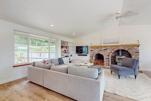A living room with a sofa, armchairs, a fireplace, and a TV. - 2BR Waterfront Home with Private Beach Access (Belfair)